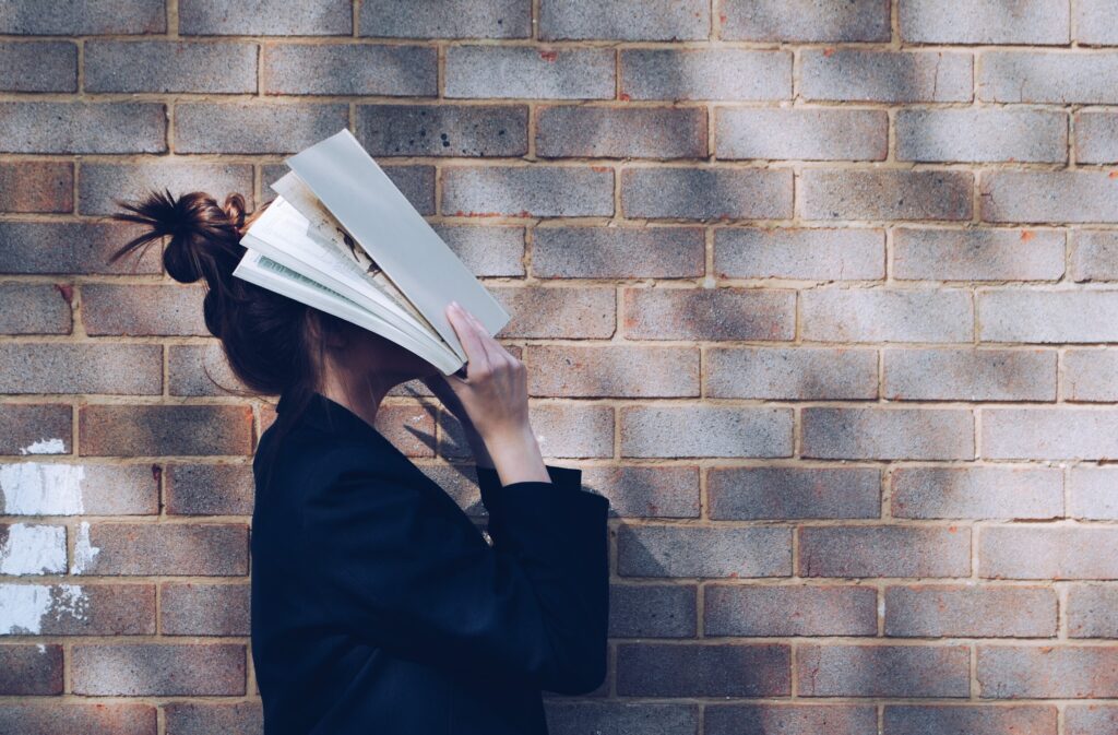 girl holds book over face