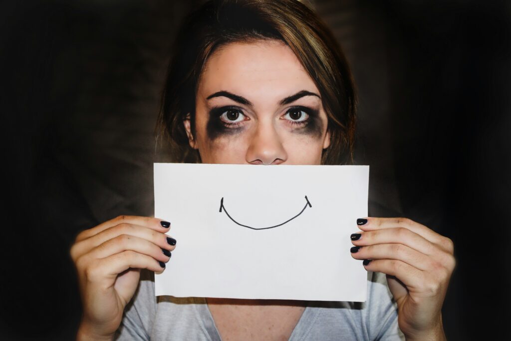 crying woman covers mouth with paper smile